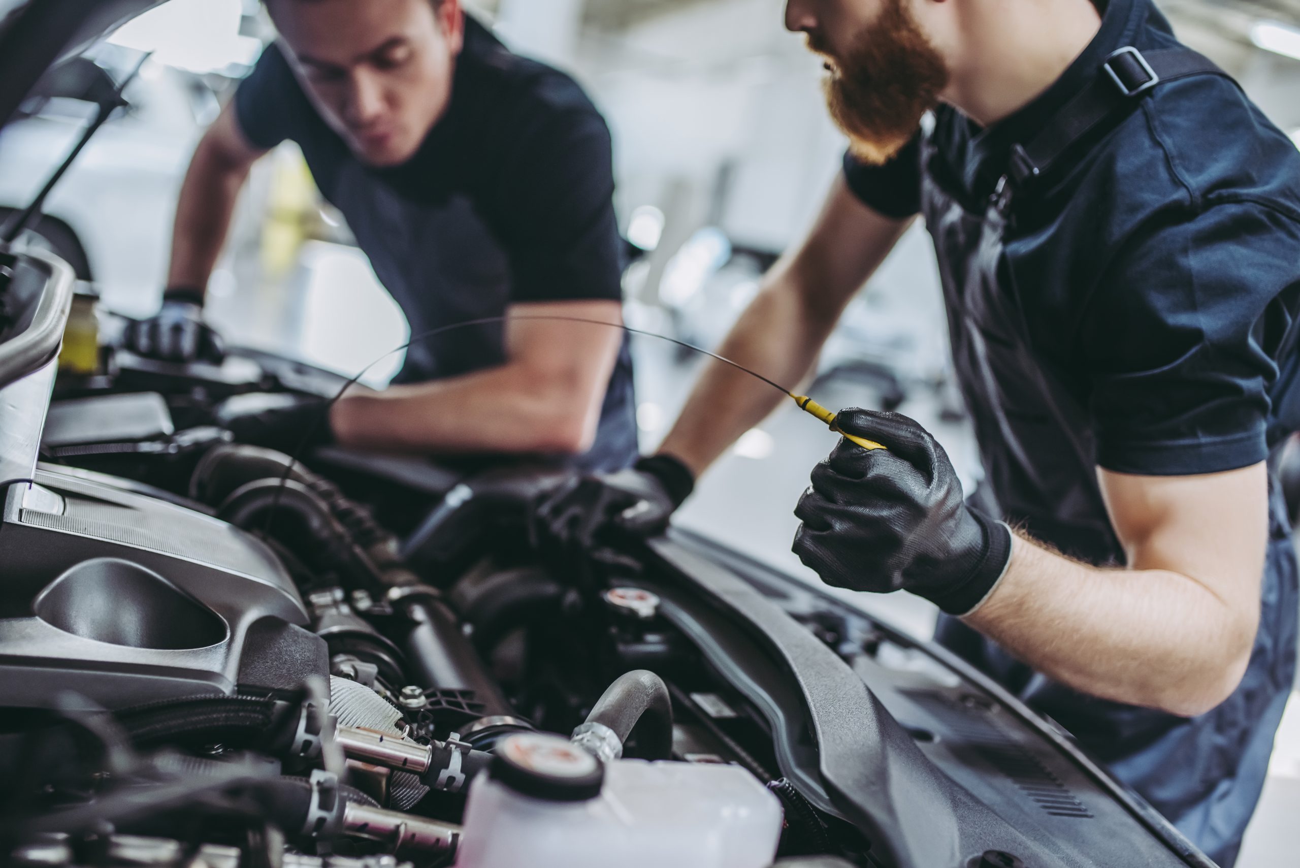 Two service technicians performing a tune-up on the engine of a Chevy vehicle